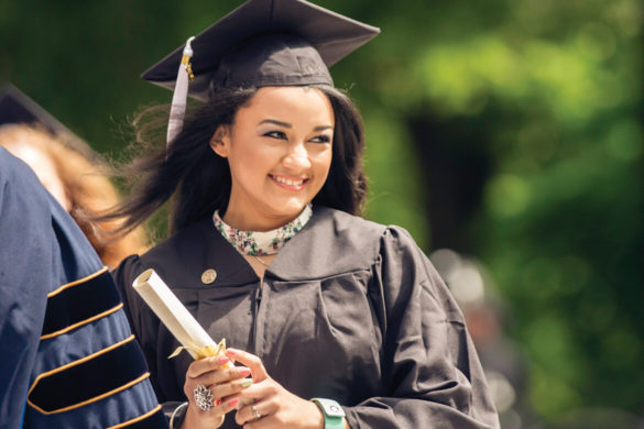 A Regent University graduate holding a diploma during the commencement ceremony in Virginia Beach.