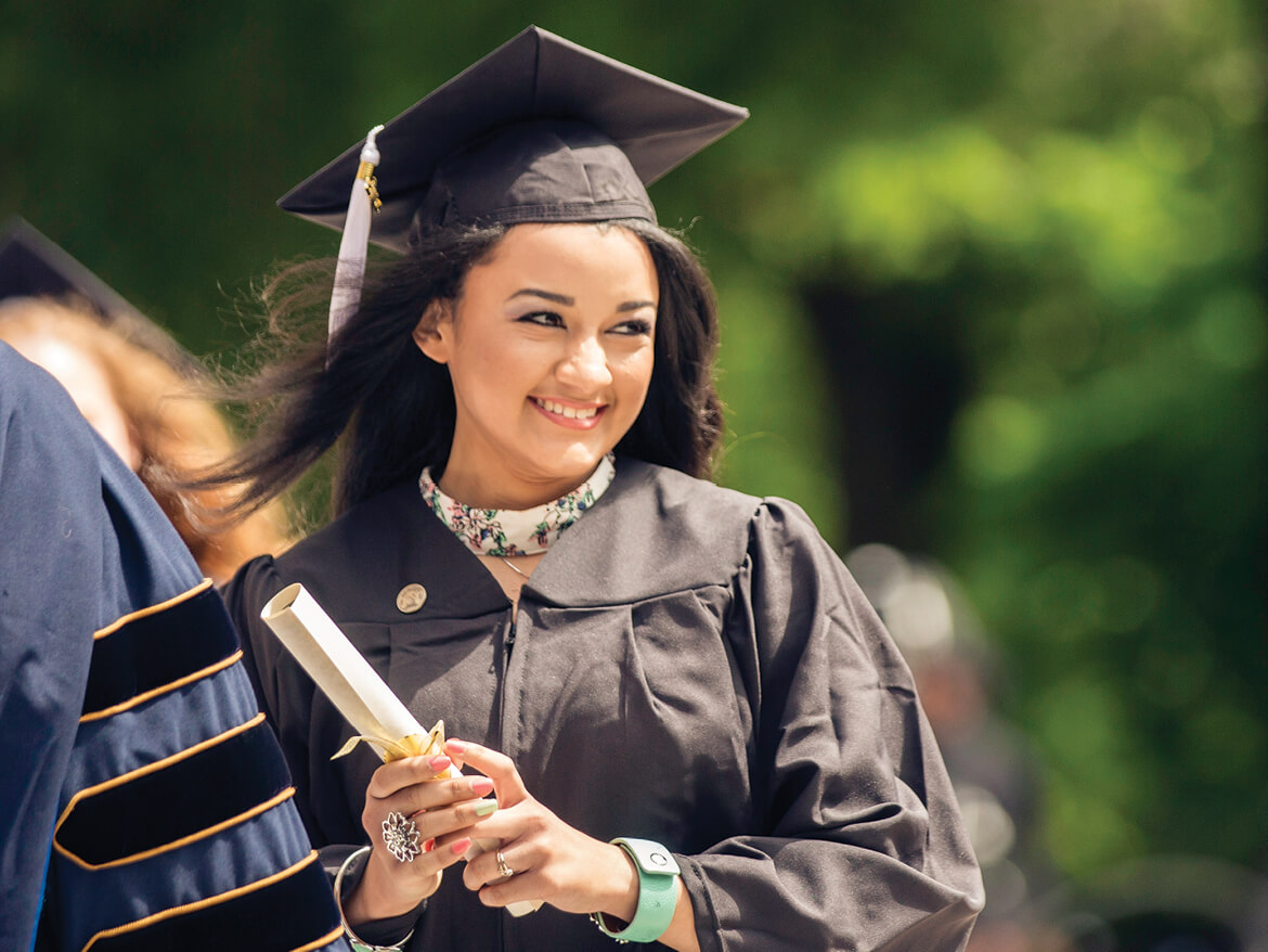 A Regent University graduate holding a diploma during the commencement ceremony in Virginia Beach.