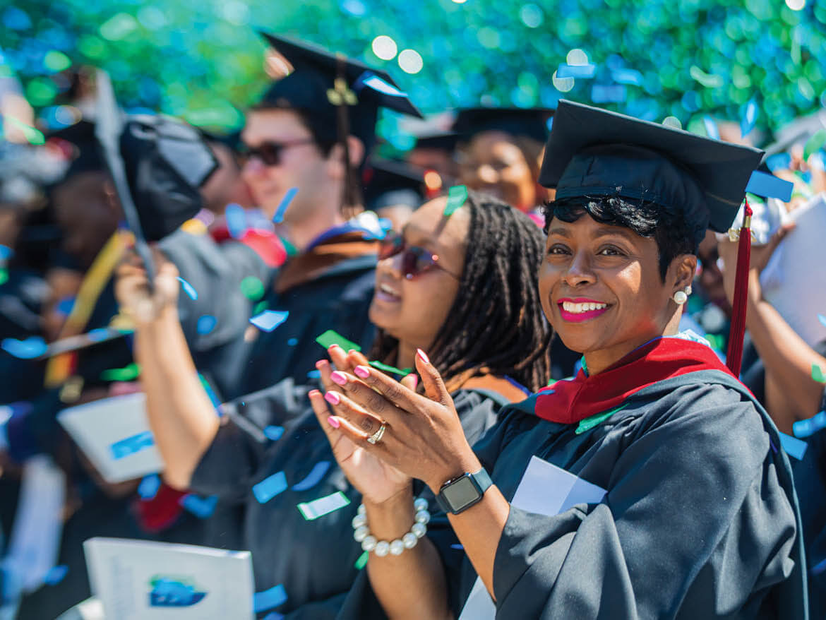 A Regent University graduate claps during the commencement ceremony in Virginia Beach.