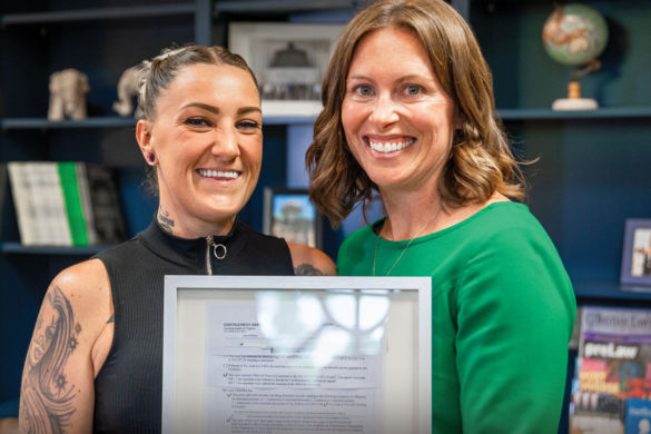 Photo of Olivia, a Trafficking survivor, holding a framed document with her lawyer: Learn more about Regent's center for global justice clinic.