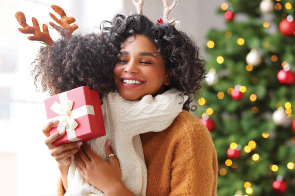 Photo of Mom hugging child in front of Christmas tree