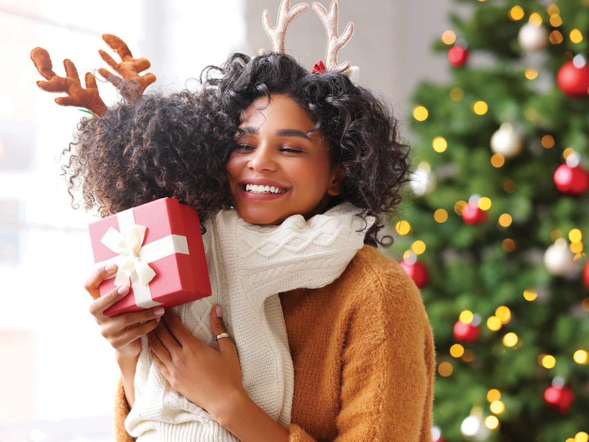 Photo of Mom hugging child in front of Christmas tree