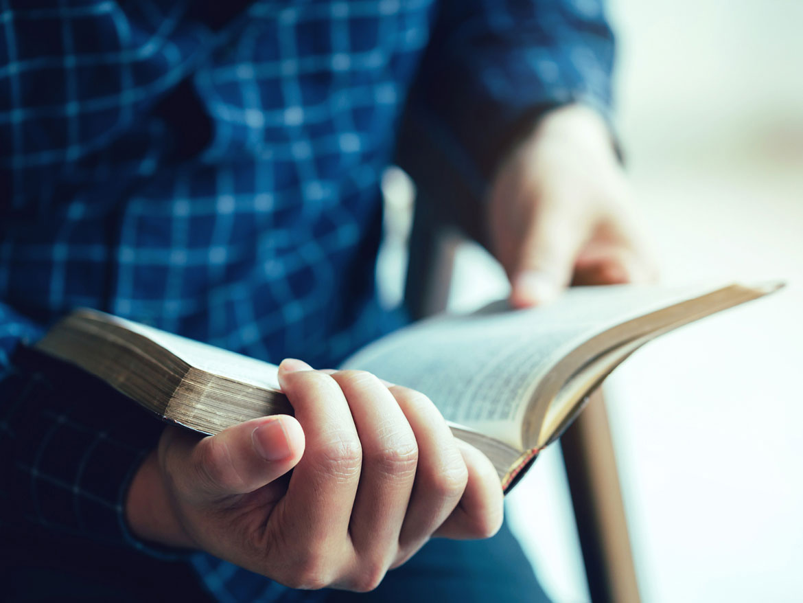 close up of hands holding a bible